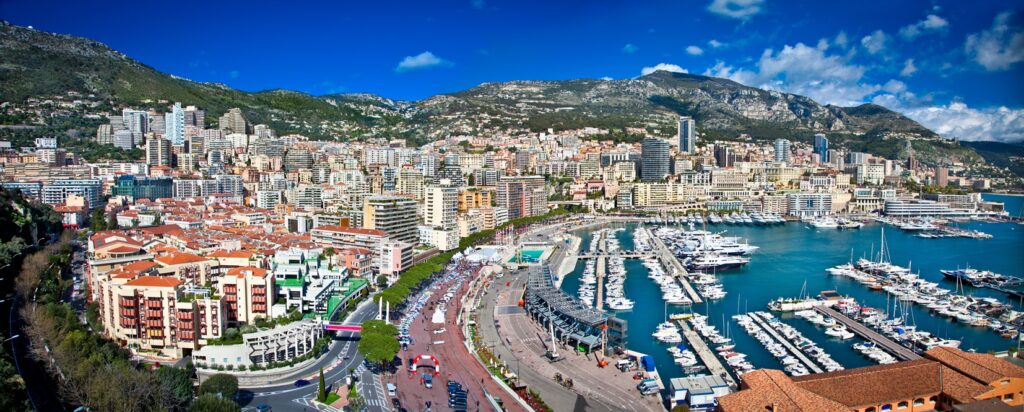Monaco – elegancja i precyzja zamiast prędkości
Monako to paradoks: jedna z najwolniejszych nit, a jednocześnie najbardziej wymagająca mentalnie. Wąskie uliczki, brak poboczy i bariery tuż przy kołach oznaczają, że o wyniku samego wyścigu często decydują kwalifikacje i bezbłędność. Atmosfera „Grand” wydarzenia – jachty, celebryci, tłum – bywa oprawą, ale kierowcy mają zero taryfy ulgowej. Najlepiej kupić bilet z dobrym dostępem do szykany przy basenie; w sklepie z pamiątkami toru znajdziesz też wyjątkowe gadżety.
